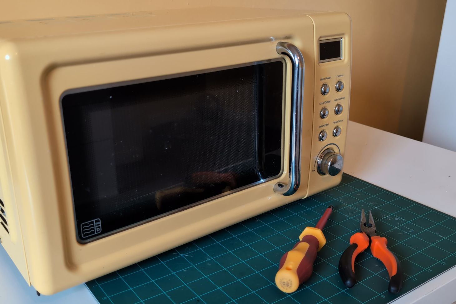 A broken microwave oven and some tools.