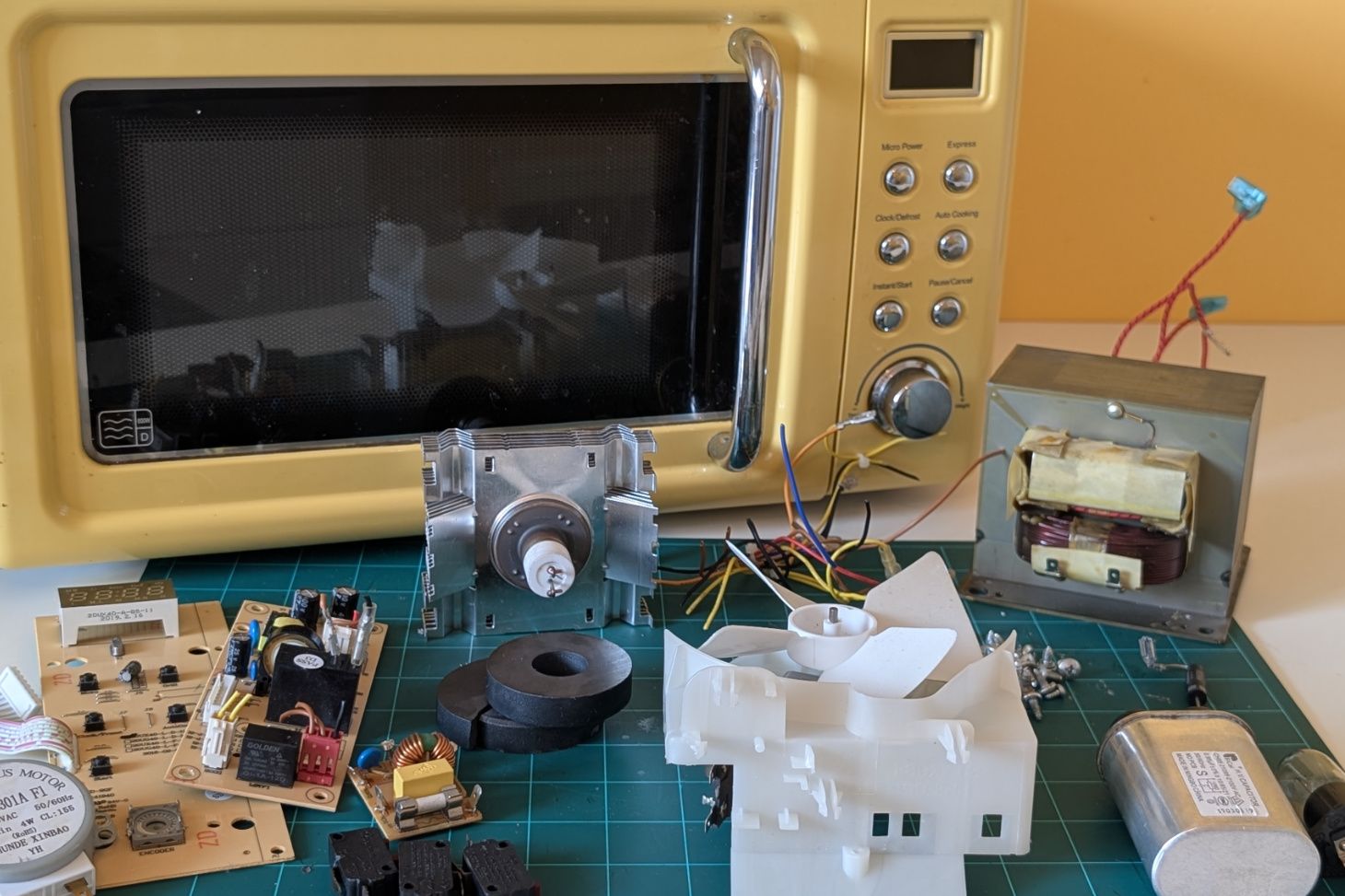 Microwave components removed and laid out in front of the microwave.