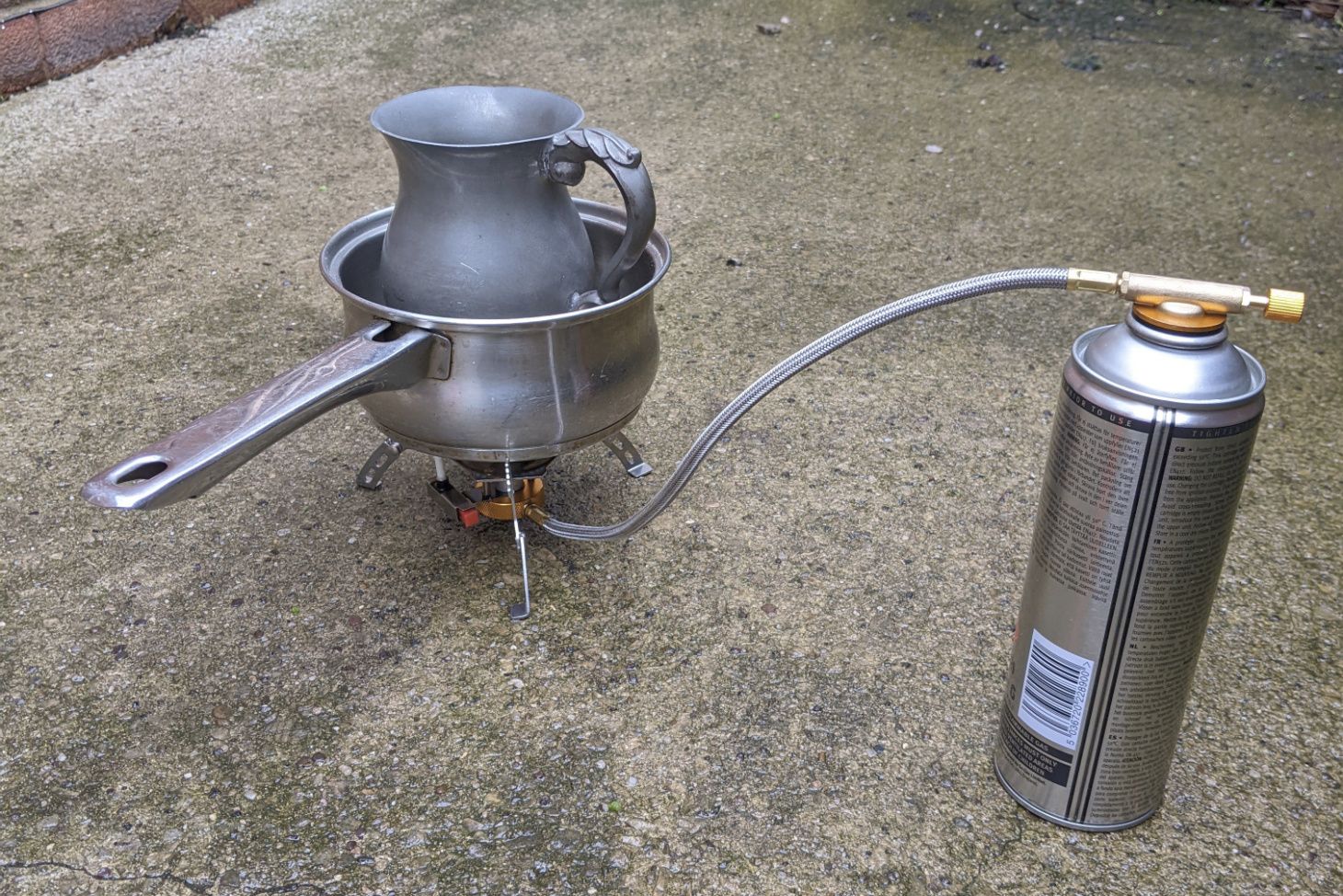 Pewter tankard ready to be melted in a saucepan over a gas camping stove.