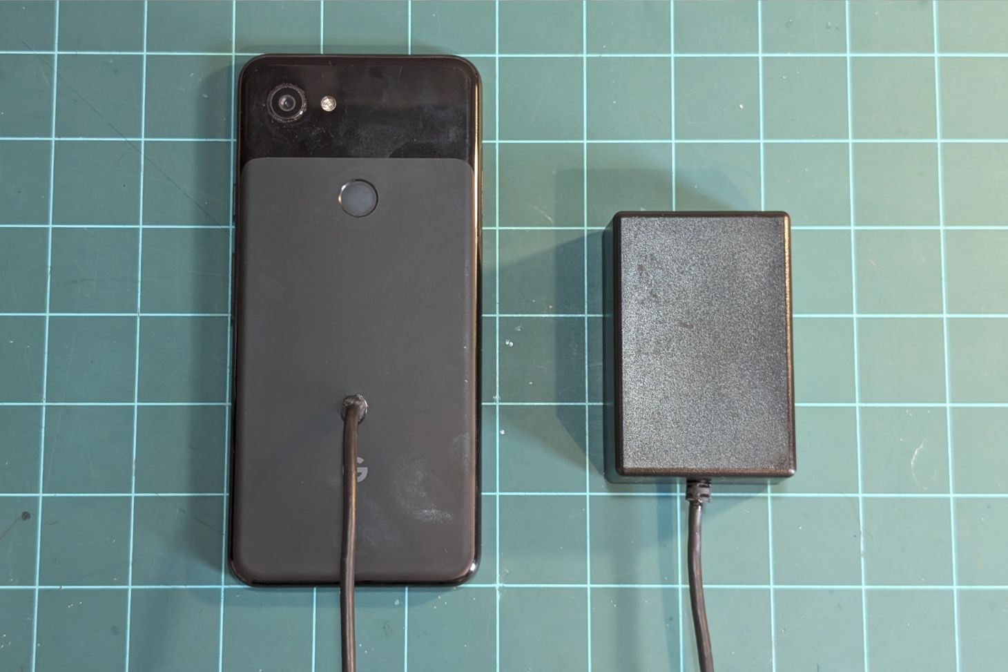 The phone face down with a hole drilled through the back and a wire fed through it.