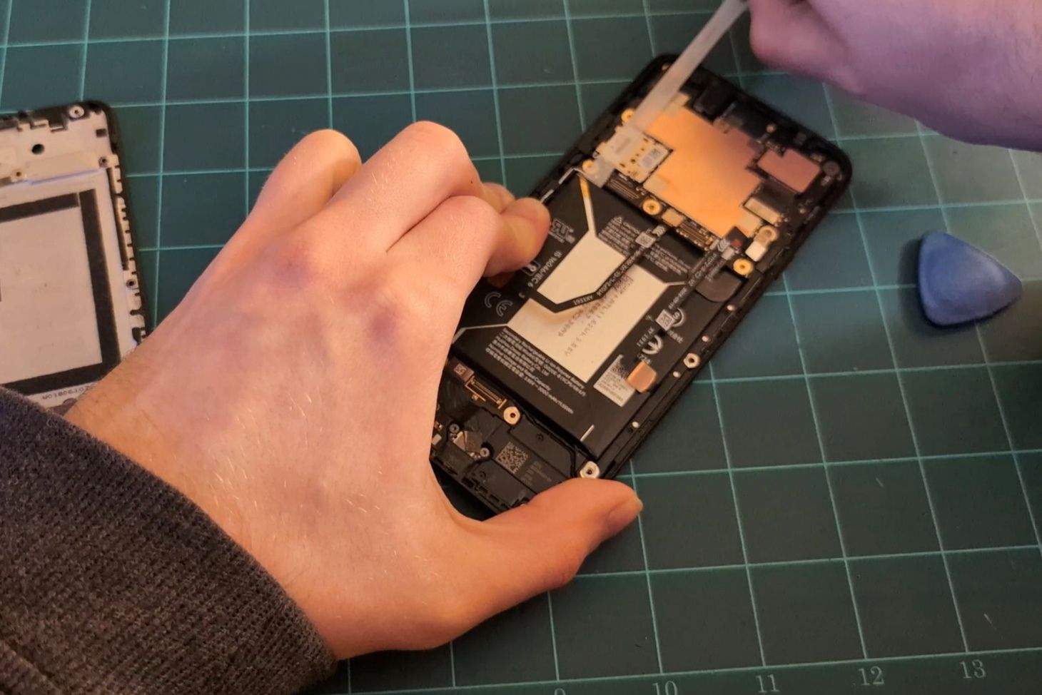 Pulling the stretch-release strip to remove the battery.