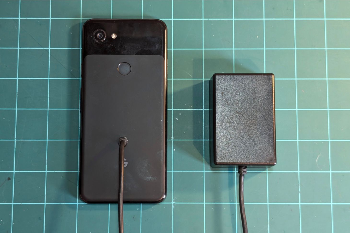 The phone face down with a hole drilled through the back and a wire fed through it.